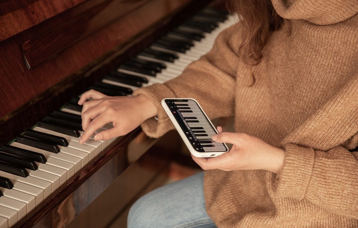 Um mulher aprendendo a tocar piano usando aplicativo em seu celular