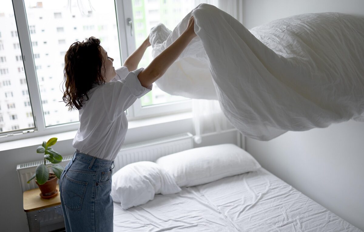 Mulher arrumando sua roupa de cama